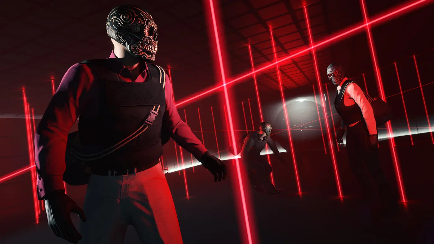 Capture officielle de GTA Online : trois braqueurs masqués de crânes stylisés, en gilet pare-balles et sacs de sport en bandoulière, progressent dans une salle entièrement quadrillée de faisceaux laser rouges verticaux et horizontaux