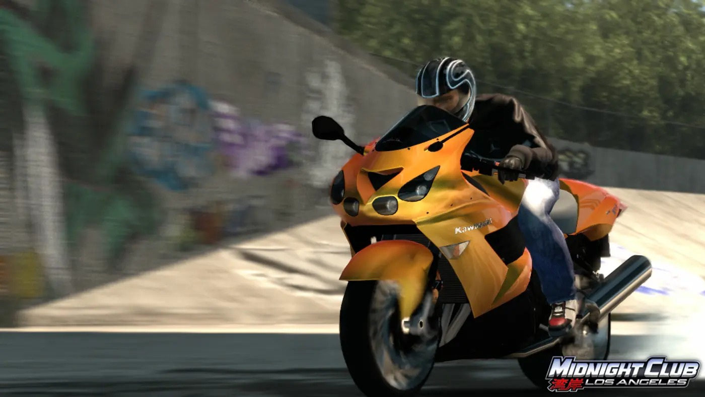 Un pilote en casque noir penché sur une superbike Kawasaki orange, lancée à pleine vitesse le long d'un mur couvert de graffitis dans Midnight Club: Los Angeles, avec un fort effet de flou de vitesse.