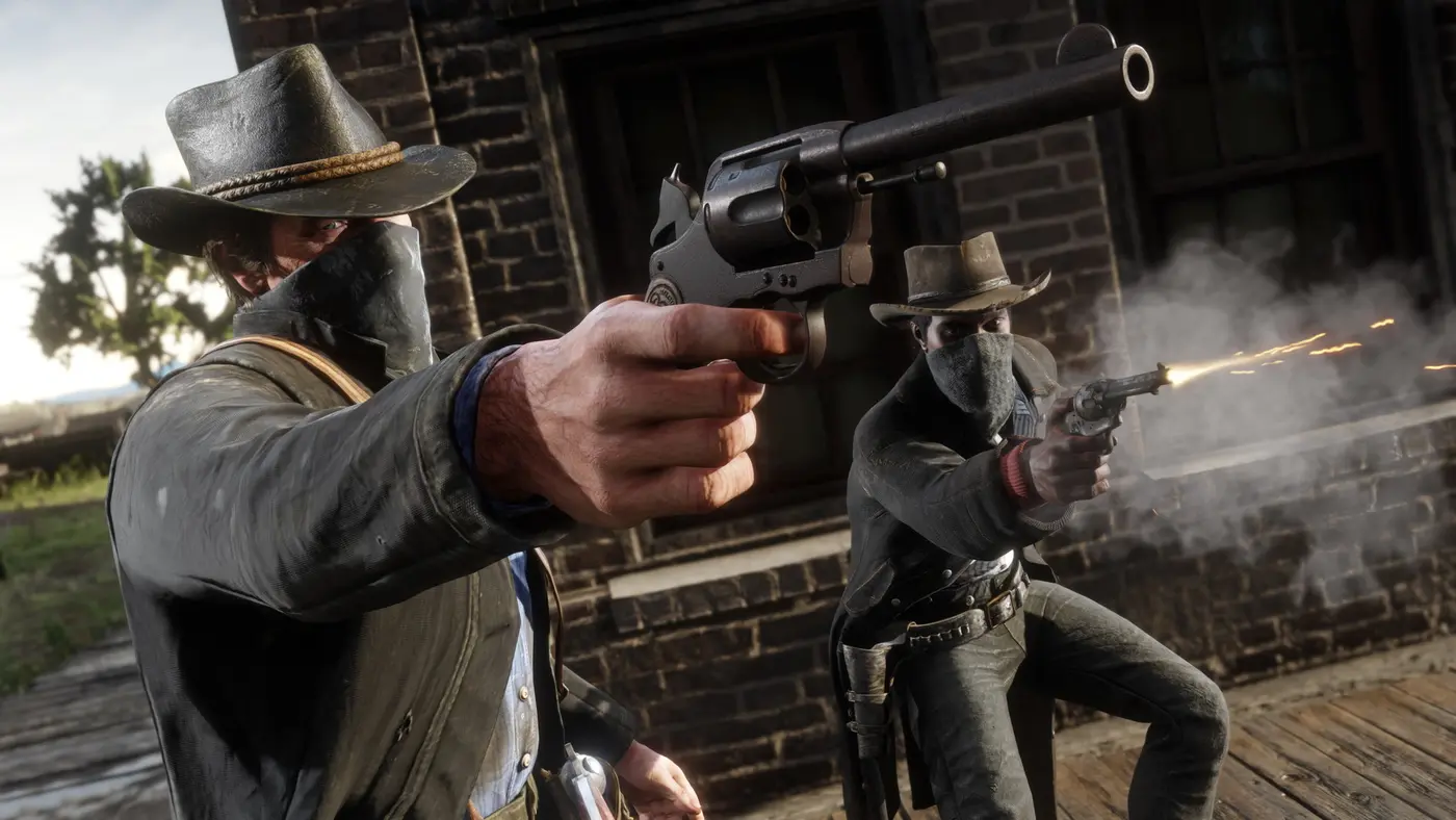 Capture officielle de Red Dead Redemption 2 : deux hors-la-loi masqués tirent au revolver vers la caméra, étincelles et fumée au bout du canon, devant une façade en brique