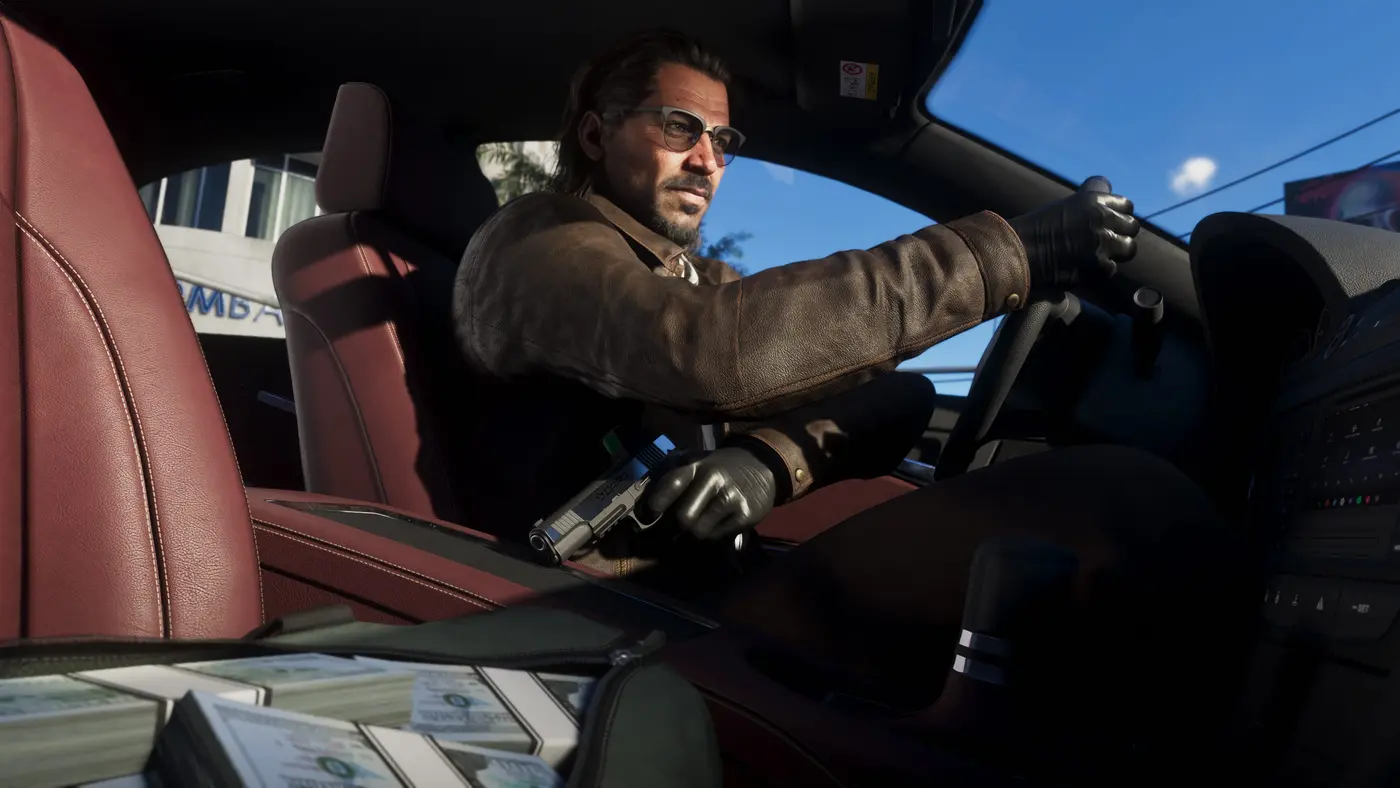 Raul Bautista au volant d'une voiture dans GTA VI, un pistolet posé sur ses genoux et des liasses de billets sur le tableau de bord, veste en cuir et gants
